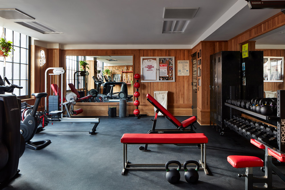 a photo of a gym with equipment that includes kettlebells, free weights and an exercise bench.