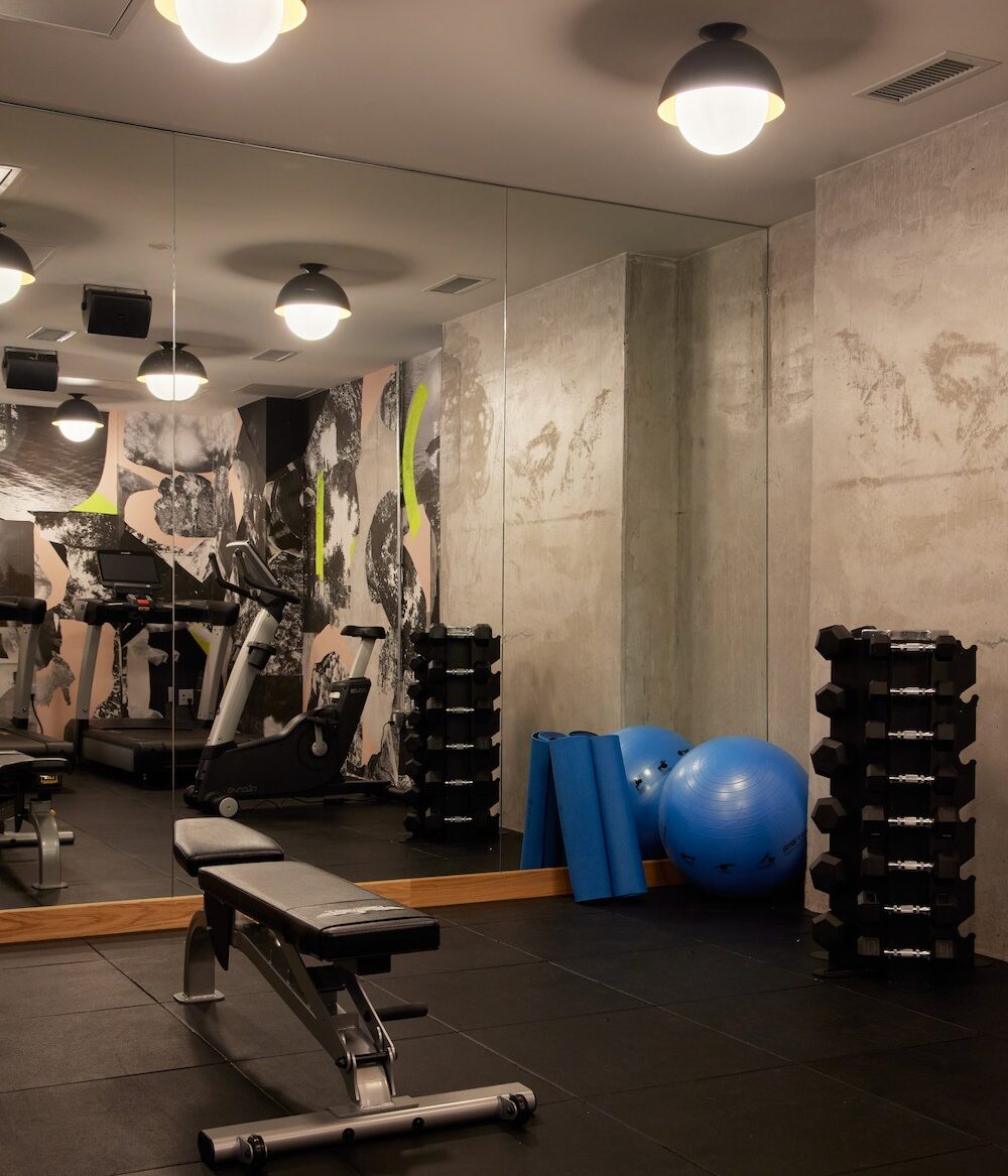 a photo of a gym with equipment that includes various free weights, giant exercise ball, yoga mats and an exercise bench.